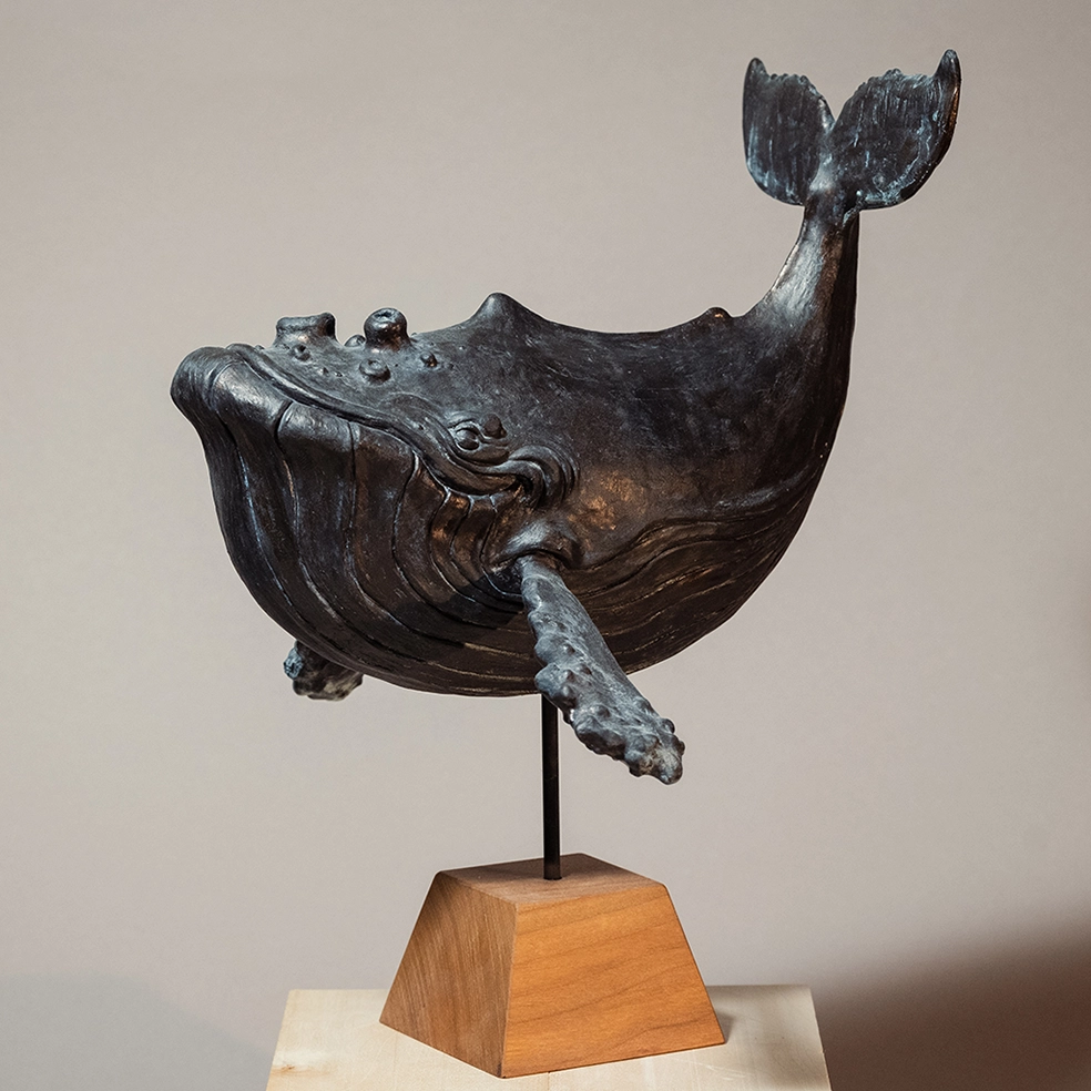 "Whale" 2018, resin casting with blue bronze patina. Created for the birth of my daughter Lila in 2018, depicting a generously curved whale, stylized in a cartoon manga style, smiling.